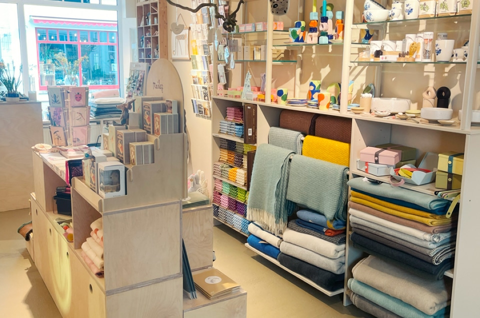 Gemütlicher Laden mit Büchern, Keramik, bunten Stoffen und Heimdekor.